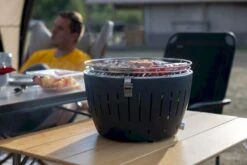 LotusGrill XL Hybrid Houtskoolbarbecue - Rood -Buiten Kamperen Winkel lotusgrill in gebruik met toppy shirtje 2